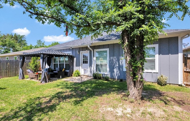back of house featuring a gazebo, board and batten siding, fence, a yard, and a patio