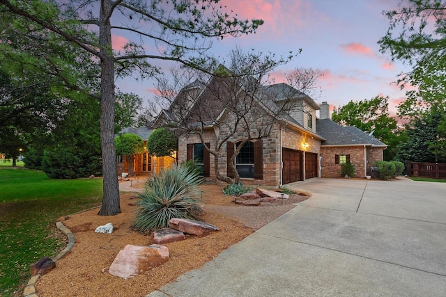view of front of home featuring concrete driveway, a chimney, a front lawn, an attached garage, and brick siding