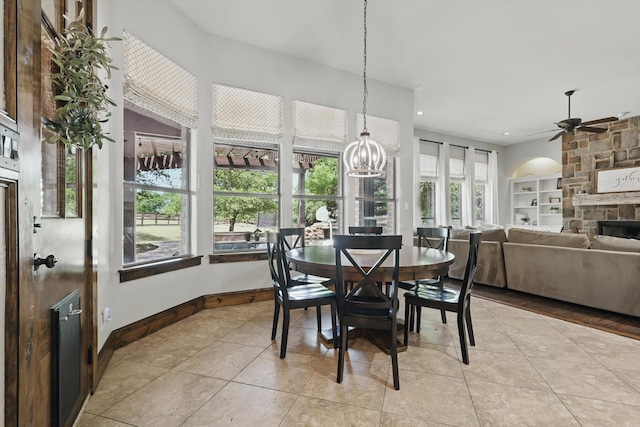 dining room featuring light tile patterned flooring, recessed lighting, built in shelves, ceiling fan with notable chandelier, and a fireplace