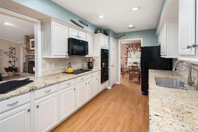 kitchen featuring backsplash, white cabinets, a sink, and black appliances