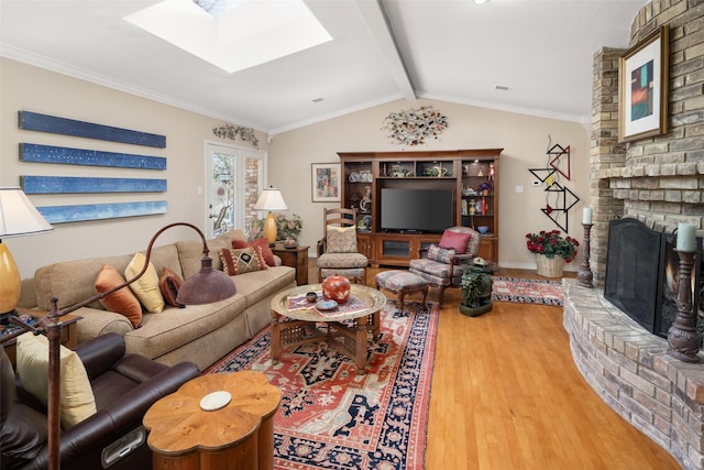 living area featuring a brick fireplace, wood finished floors, and vaulted ceiling with skylight