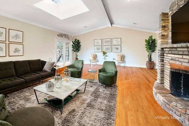 living area featuring a fireplace, vaulted ceiling with skylight, wood finished floors, and ornamental molding