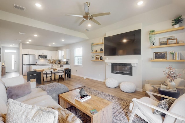 3238 Baehr Dr, Royse City, TX 75189 - living area with light wood finished floors, a ceiling fan, baseboards, a glass covered fireplace, and recessed lighting