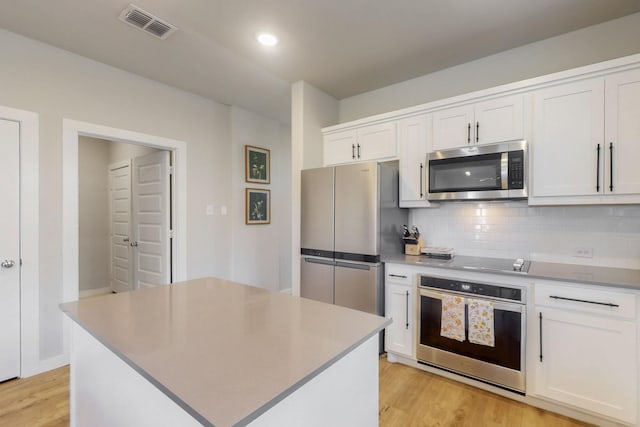 3238 Baehr Dr, Royse City, TX 75189 - kitchen with stainless steel appliances, light wood-style floors, backsplash, white cabinetry, and a kitchen island