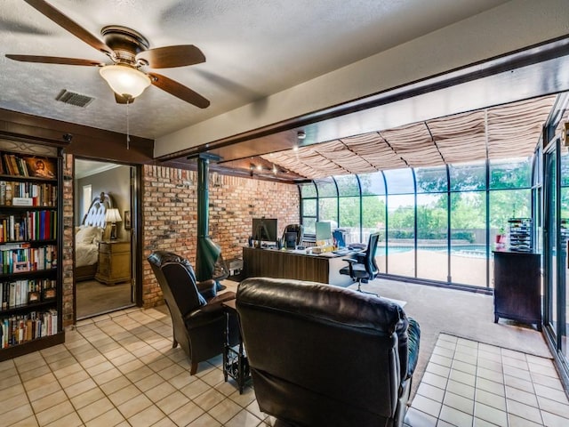 interior space with a wood stove, visible vents, brick wall, and ceiling fan