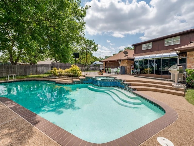 view of pool with fence, a patio, and a pool with connected hot tub