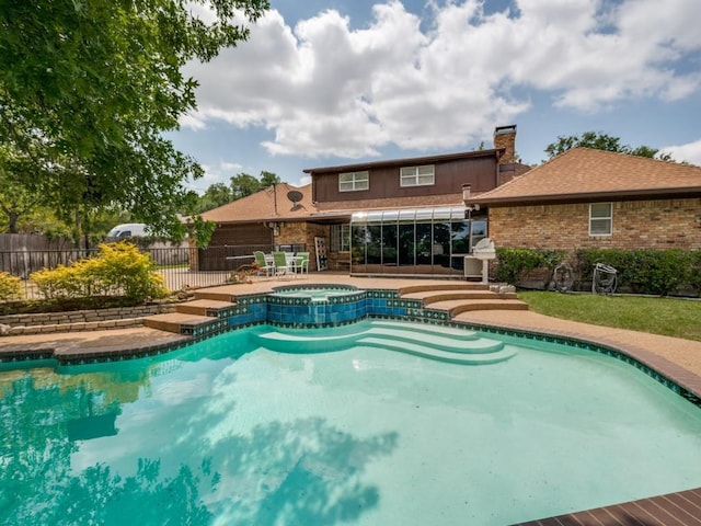 view of swimming pool featuring fence, a pool with connected hot tub, and a patio