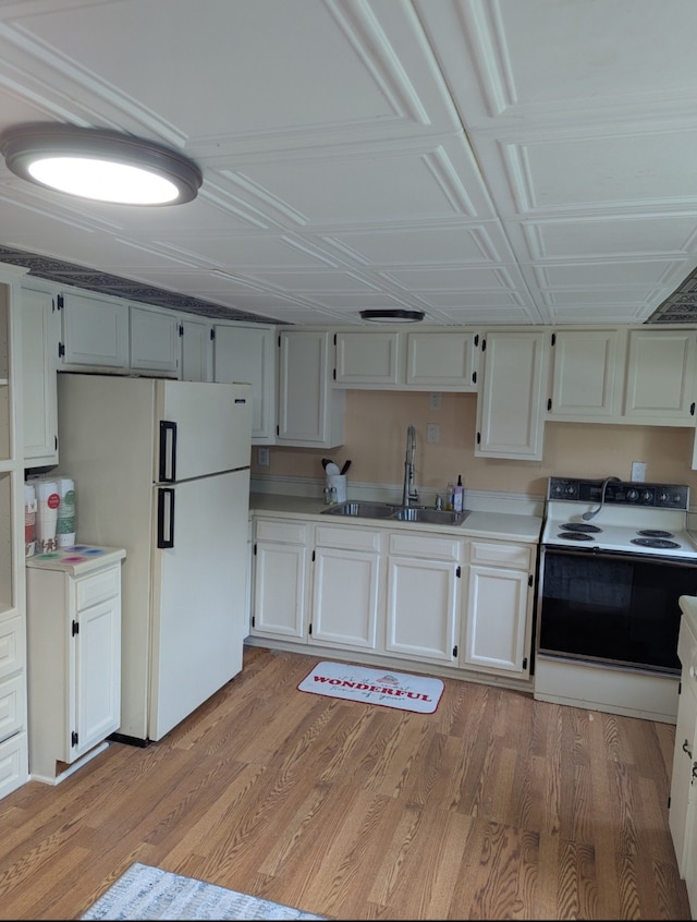 kitchen featuring light wood-style flooring, a sink, freestanding refrigerator, electric range oven, and light countertops