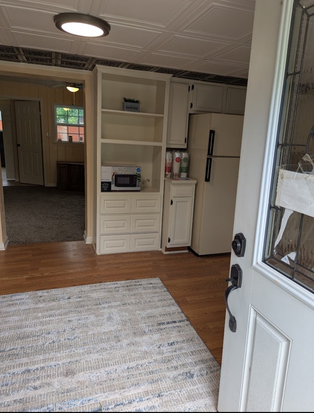 kitchen with black microwave, open shelves, dark wood-type flooring, and freestanding refrigerator