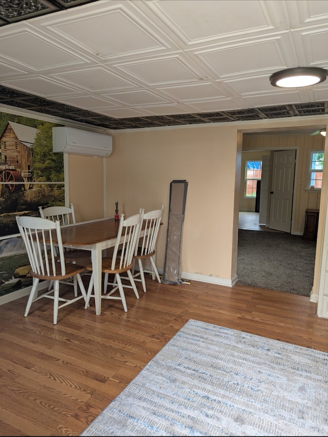 dining space featuring baseboards, wood finished floors, a wall mounted AC, and an ornate ceiling