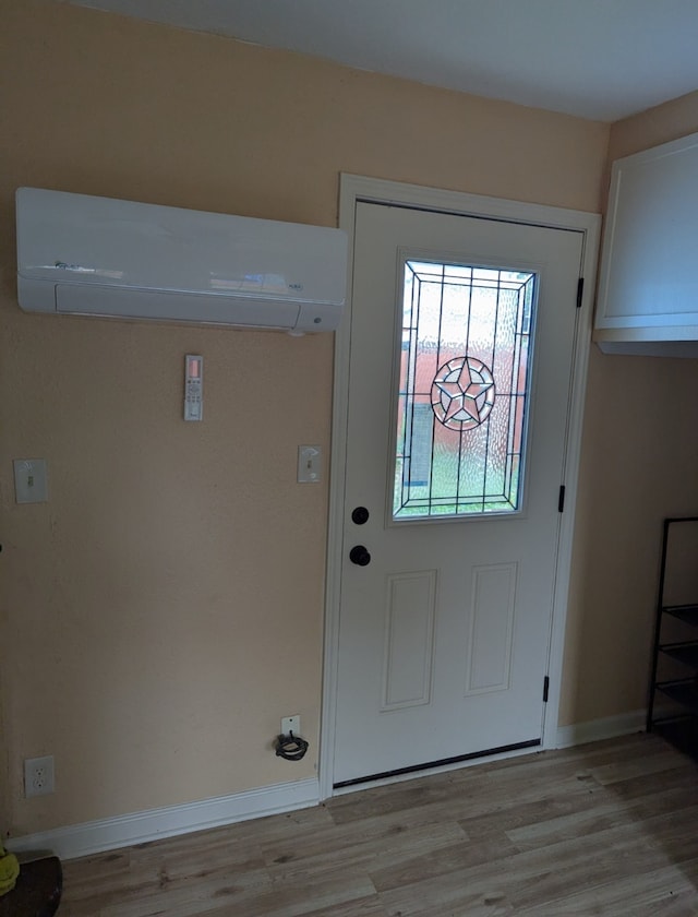 entryway with baseboards, light wood-style flooring, and an AC wall unit