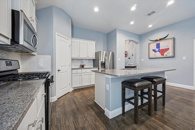511 Ranchwood Dr, Justin, TX 76247 - kitchen featuring stainless steel appliances, dark wood-style flooring, a sink, a kitchen breakfast bar, and white cabinetry
