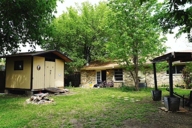 exterior space with a storage shed, an outbuilding, cooling unit, fence, and a lawn