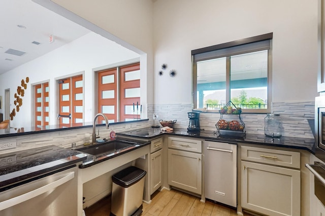 kitchen with light wood-type flooring, decorative backsplash, a sink, and dark countertops