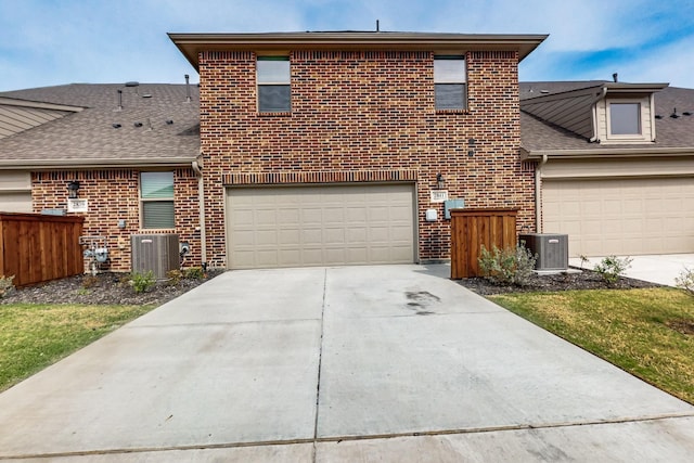 traditional-style house with brick siding, central air condition unit, and concrete driveway