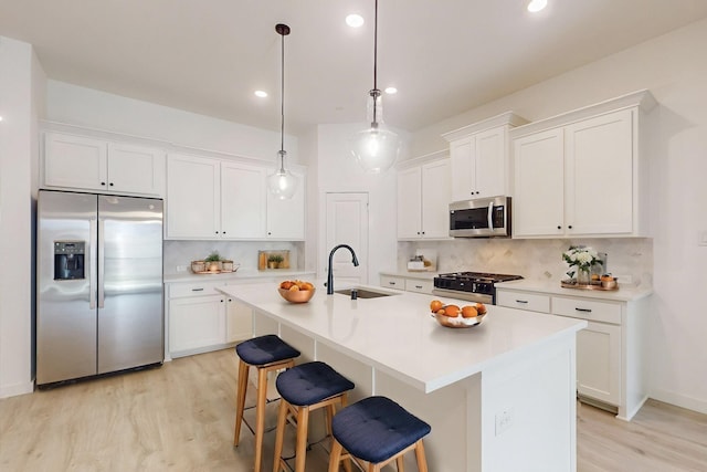 kitchen with light wood-style floors, tasteful backsplash, stainless steel appliances, and a sink
