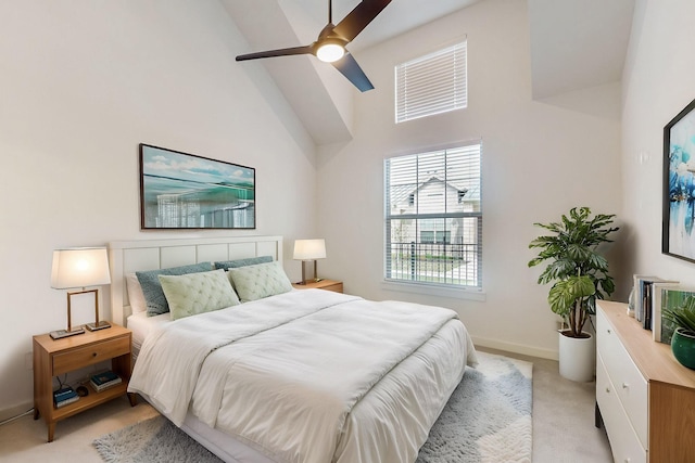 bedroom featuring light carpet, baseboards, a high ceiling, and a ceiling fan