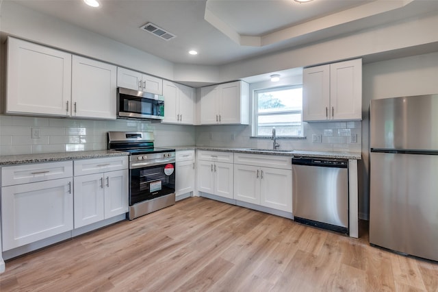 604 N E St, Arlington, TX 76011 - kitchen with white cabinets, light wood finished floors, a sink, visible vents, and appliances with stainless steel finishes