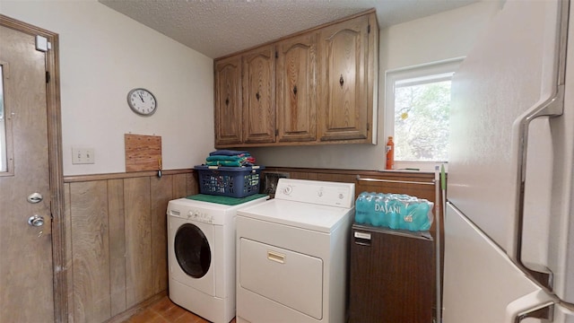 1351 Porter Ct, Granbury, TX 76048 - laundry area featuring a wainscoted wall, a textured ceiling, light wood-type flooring, separate washer and dryer, and cabinet space