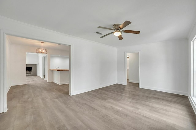 empty room featuring ceiling fan, ornamental molding, wood finished floors, and visible vents
