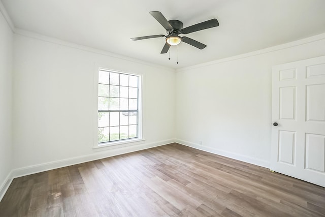 empty room with wood finished floors, baseboards, and ornamental molding