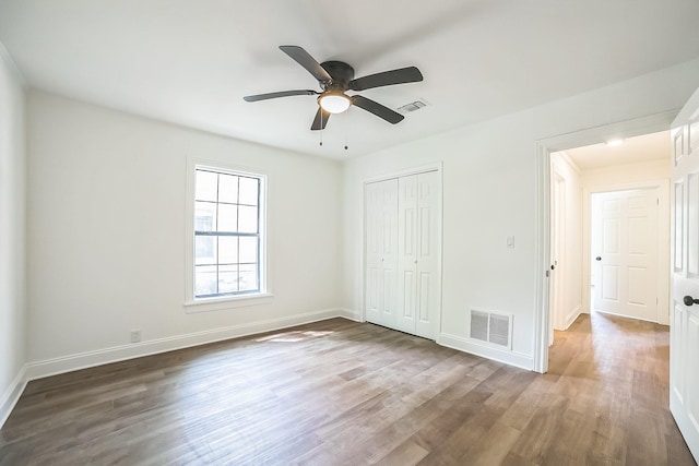 unfurnished bedroom with a closet, wood finished floors, and visible vents