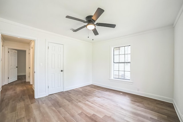 unfurnished bedroom with a ceiling fan, crown molding, wood finished floors, a closet, and baseboards