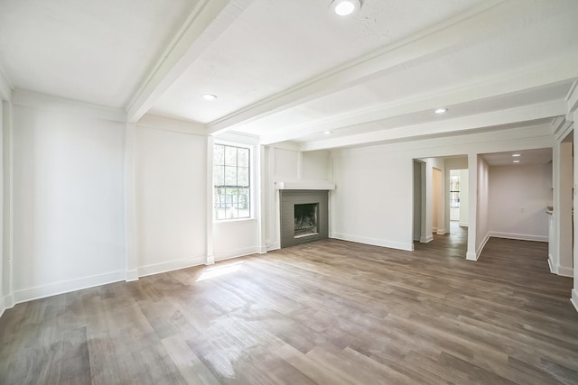 unfurnished living room with recessed lighting, wood finished floors, beamed ceiling, baseboards, and a fireplace