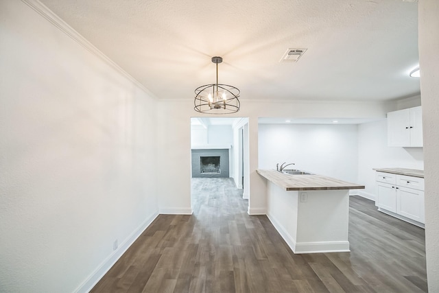 kitchen featuring dark wood finished floors, visible vents, white cabinetry, and a sink