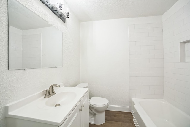 bathroom with a textured ceiling, toilet, wood finished floors, a textured wall, and vanity