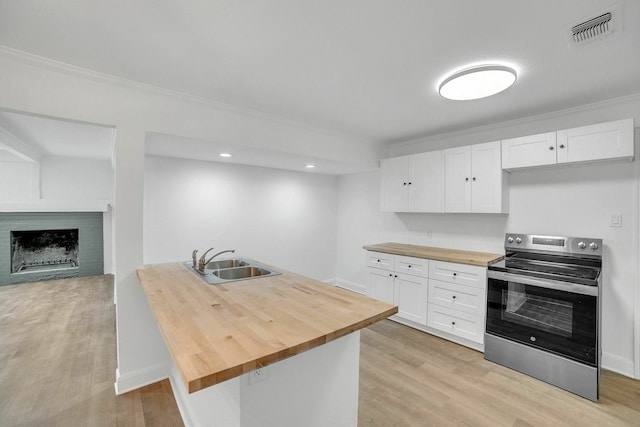 kitchen with white cabinets, a sink, electric range, visible vents, and wooden counters