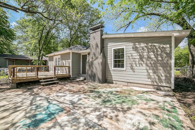 back of house featuring fence, a patio, a chimney, and a deck