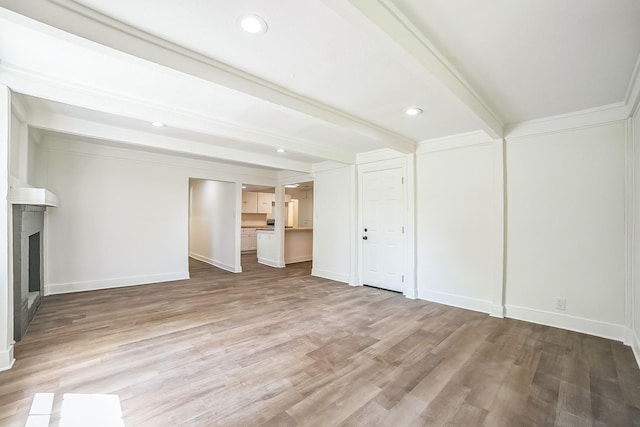 unfurnished living room featuring beamed ceiling, light wood-style flooring, baseboards, and a fireplace