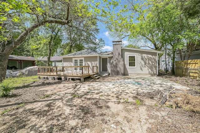back of property featuring fence, a chimney, and a deck