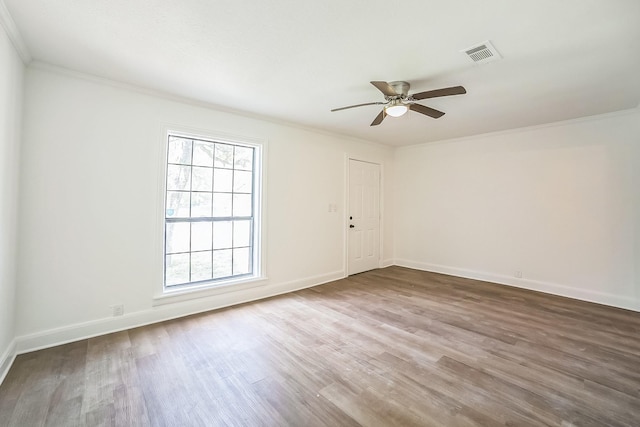 empty room featuring wood finished floors, visible vents, ornamental molding, and a healthy amount of sunlight