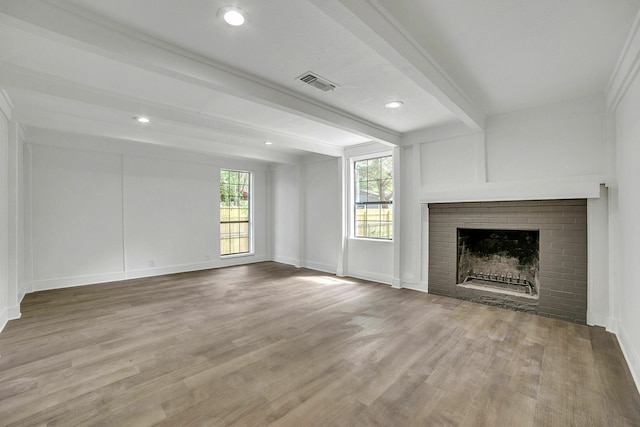 unfurnished living room with beamed ceiling, light wood finished floors, visible vents, and a fireplace