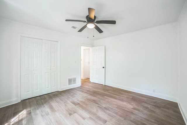unfurnished bedroom with wood finished floors, visible vents, and baseboards