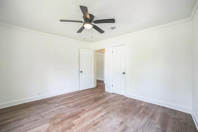 unfurnished bedroom featuring baseboards, crown molding, wood finished floors, and visible vents