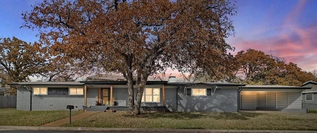 view of front of house with brick siding, a lawn, and a carport