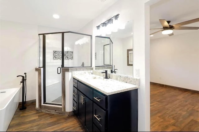 bathroom featuring a shower stall, wood finished floors, vanity, ceiling fan, and a freestanding bath