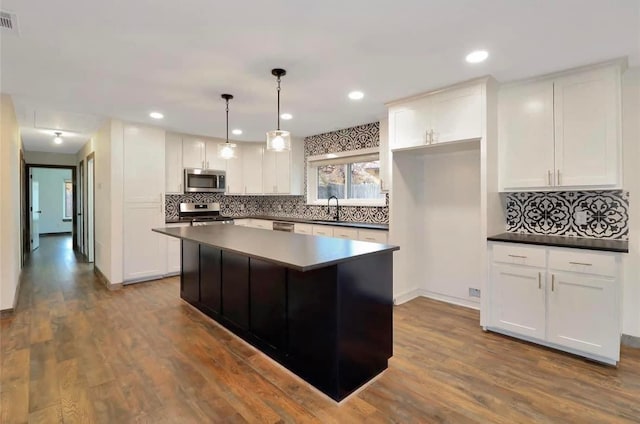 kitchen with decorative backsplash, stainless steel appliances, a sink, and white cabinetry