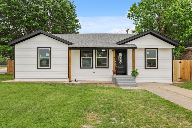 ranch-style home featuring a front yard, a shingled roof, and fence