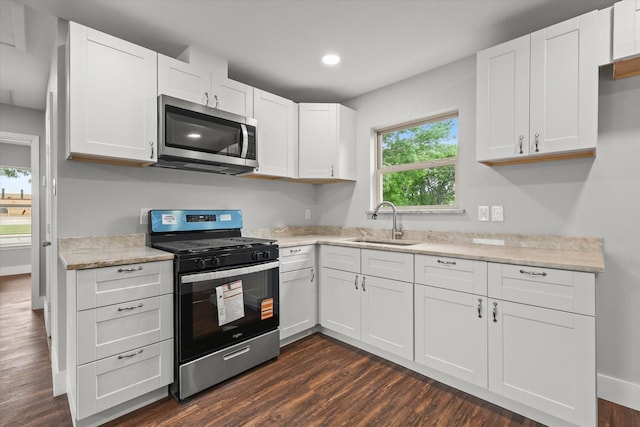 kitchen featuring white cabinetry, stainless steel appliances, dark wood-style floors, and a sink
