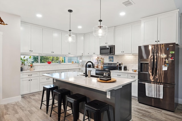 kitchen with light wood-type flooring, stainless steel appliances, visible vents, and backsplash