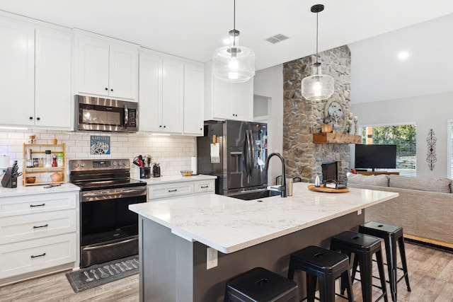 kitchen with light wood finished floors, tasteful backsplash, open floor plan, visible vents, and appliances with stainless steel finishes