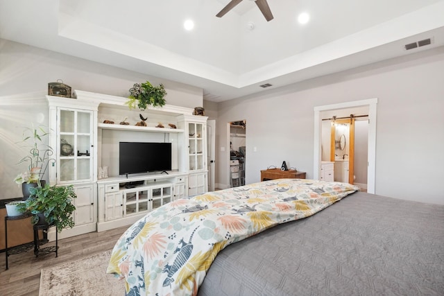 bedroom featuring a barn door, a ceiling fan, light wood-type flooring, visible vents, and recessed lighting