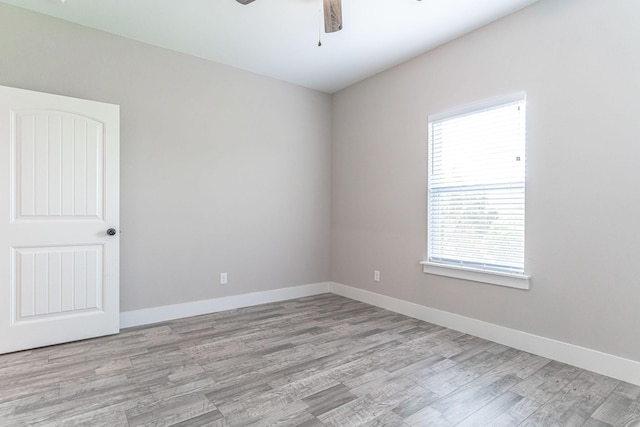 spare room featuring wood finished floors, a healthy amount of sunlight, and ceiling fan