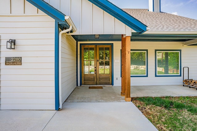 entrance to property featuring board and batten siding, a shingled roof, french doors, and a porch