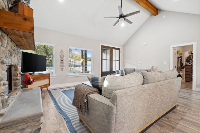 living room featuring a ceiling fan, french doors, light wood-type flooring, beam ceiling, and high vaulted ceiling