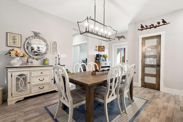 dining area featuring light wood-style flooring, baseboards, and an inviting chandelier